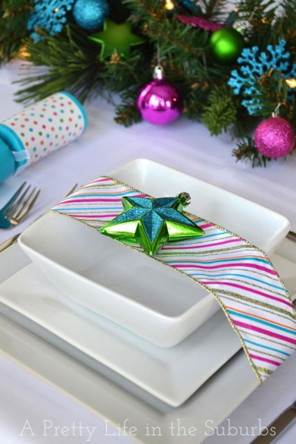 Dettaglio tavola colorata con piatti in ceramica bianca, nastro multicolore e stella verde e blu